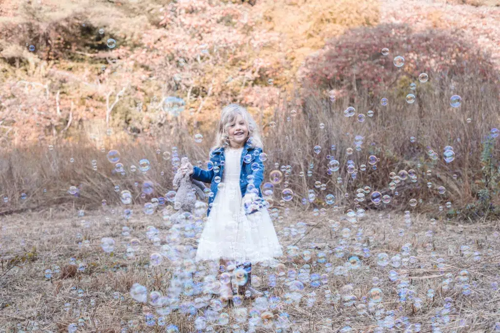 A Young Girl Playing With A Bubble Machine