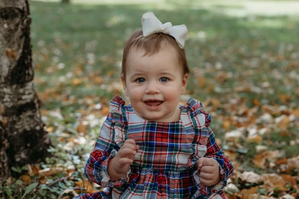 a Toddler Wearing Baby And Toddler Clothing Is Playing In The Grass Outdoors During The Fall Season.