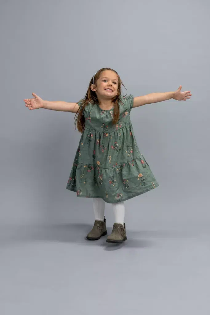 A person dressed in a colorful dress is smiling and dancing joyfully.