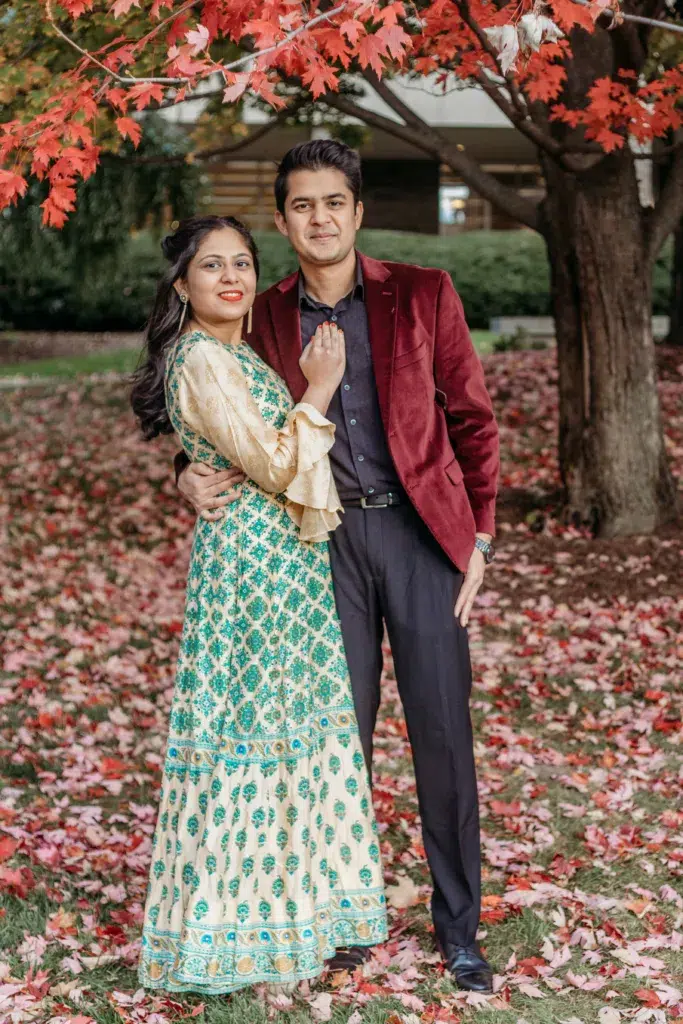 Engaged Indian couple in traditional clothing hugging under fall foliage