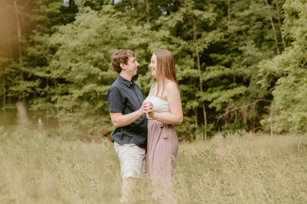 Two People Are Posing In A Field Of Tall Grass.