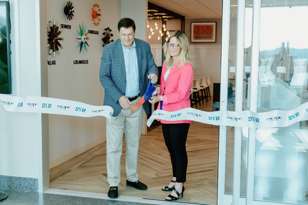 Two people cutting a ribbon at an indoor ceremony.