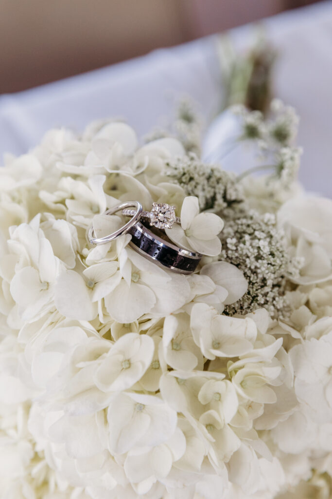 White hydrangea bouquet with a diamond engagement ring nestled among the petals.