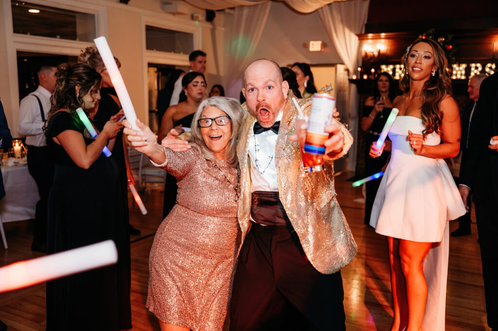 A lively party scene shows people in festive attire enjoying light sticks and drinks, capturing a joyful, celebratory atmosphere indoors.