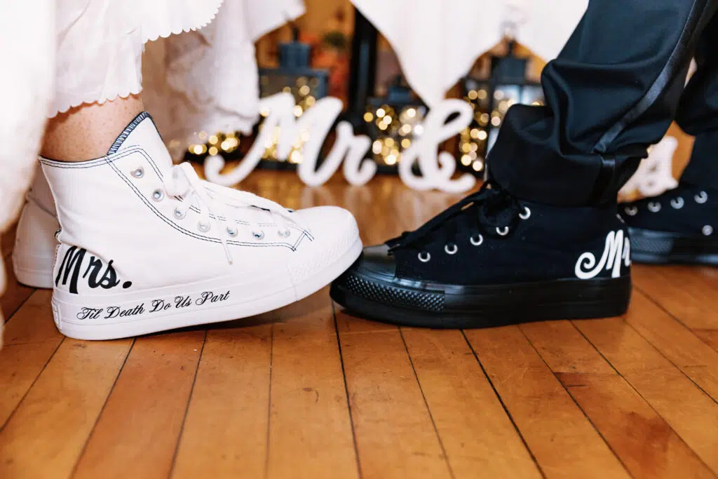Two people wearing custom sneakers labeled