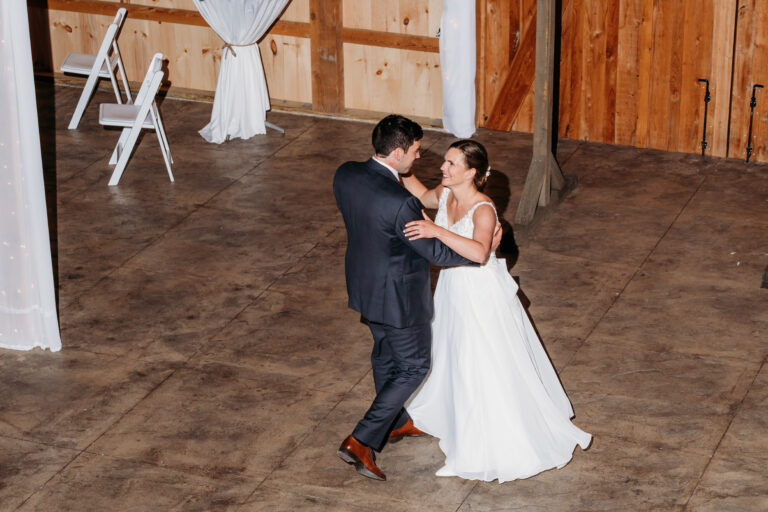 Bride and groom dancing together in a rustic wooden barn.