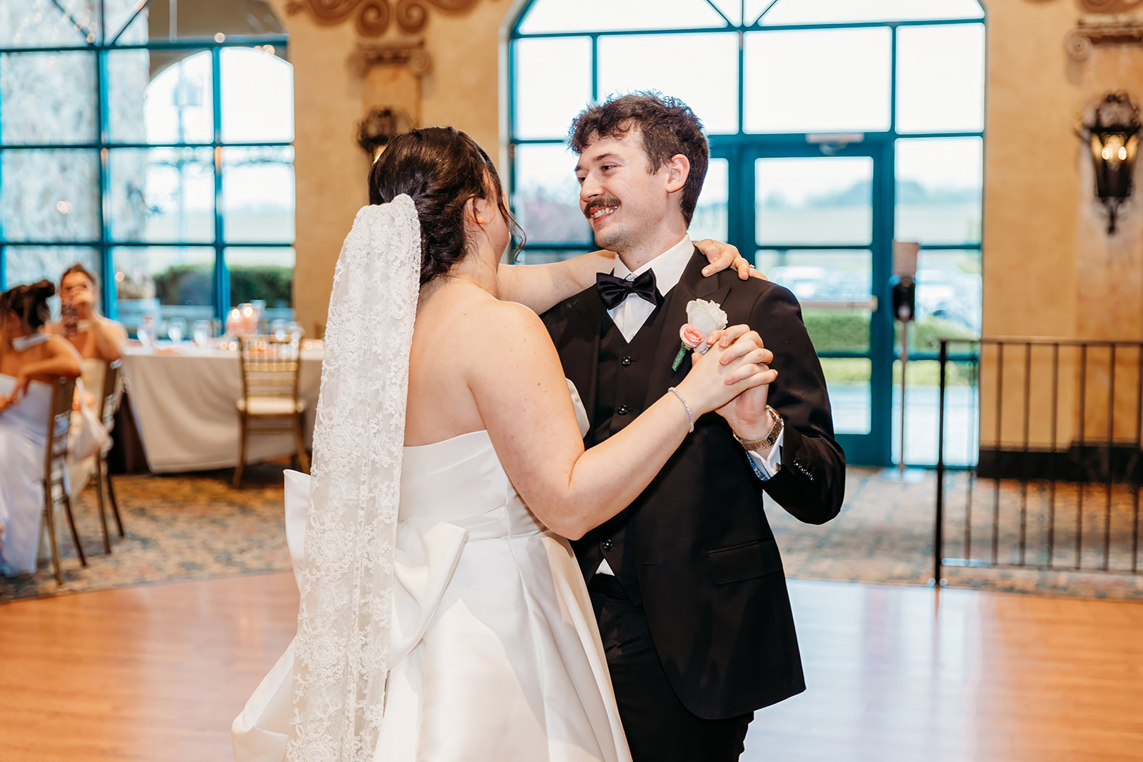 Bride and groom dancing together at their wedding reception in a bright, elegant venue.